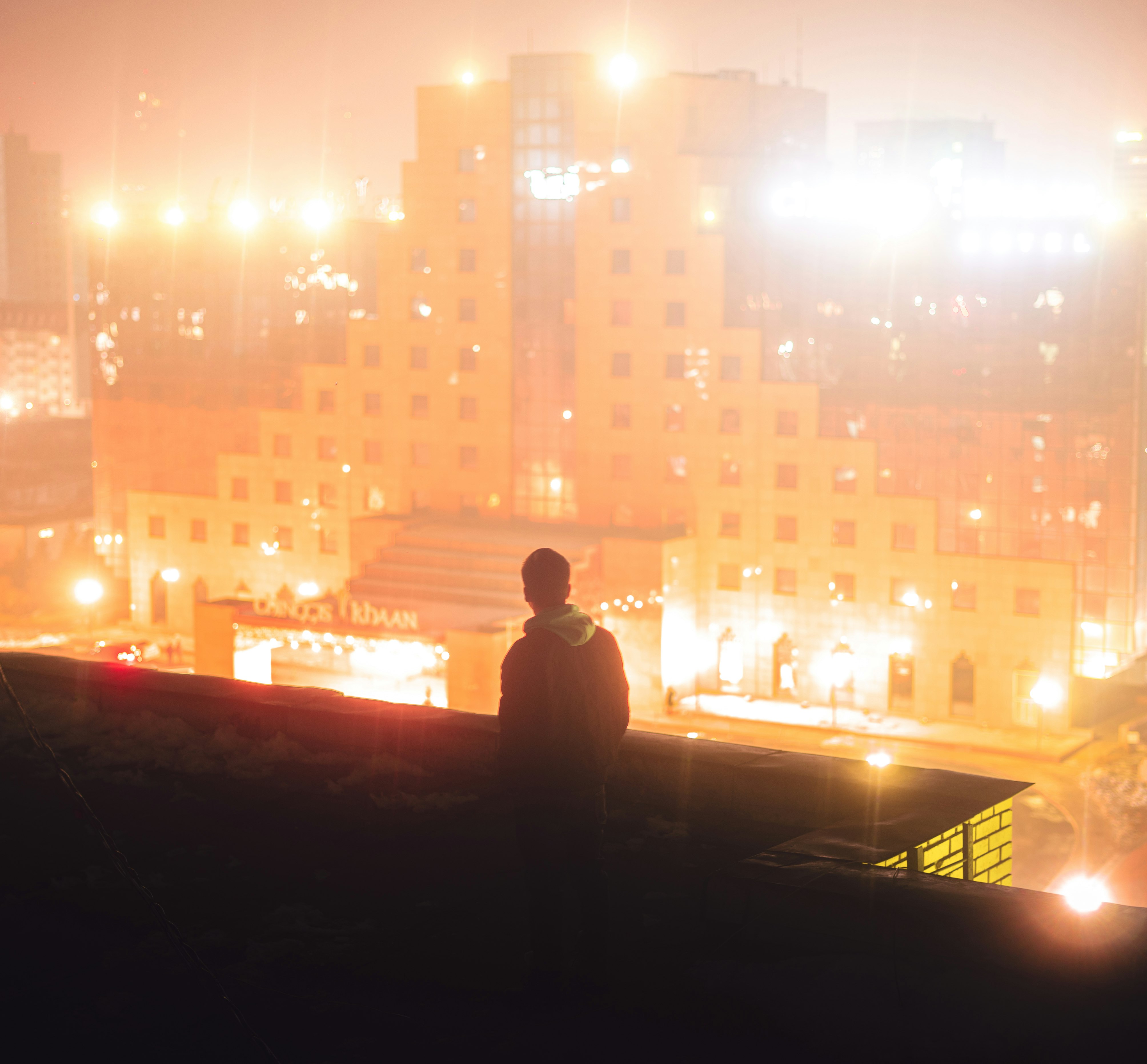 silhouette of man standing on roof top during night time